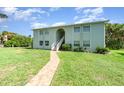 Exterior shot of a two-story condo building featuring a brick walkway and well-maintained lawn at 522 Pine Ave # 8B, Anna Maria, FL 34216