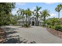 Expansive front exterior of the home, including the circular driveway and lush palm trees at 6959 Westchester Cir, Bradenton, FL 34202
