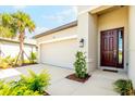 Close-up of the garage, walkway, and entrance, highlighting the beautiful brown front door and manicured landscaping at 9292 Tequila Sunrise Dr, Sarasota, FL 34241