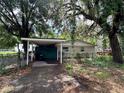 Quaint home with a carport and mature trees, offering a peaceful and shady outdoor space at 9344 Peony St, New Port Richey, FL 34654