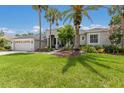Beautiful single-story home featuring a lush green lawn and attractive landscaping with mature palm trees at 10022 Laurel Valley Avenue Cir, Bradenton, FL 34202