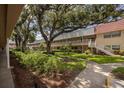 Exterior view of condo complex highlighting mature trees, walkways, landscaping and exterior stairways at 10037 62Nd N Ter # 23, St Petersburg, FL 33708