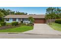 Single-story home featuring a well-kept lawn, tropical landscaping, and a spacious driveway at 1004 68Th Nw St, Bradenton, FL 34209