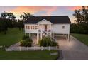 Charming two-story waterfront home featuring a white picket fence, lush landscaping, and elevated construction at 1610 Bayshore Dr, Terra Ceia, FL 34250