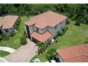 Aerial view of a two-story home with a terracotta tile roof and a brick driveway, surrounded by green landscaping at 20940 Valore Ct, Venice, FL 34293