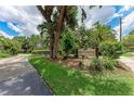 Community entrance sign surrounded by trees, lush landscaping, and a sidewalk for a welcoming neighborhood feel at 2237 Circlewood Dr # 18, Sarasota, FL 34231