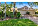 Inviting single-story home featuring a brick driveway and lush, colorful landscaping at 2411 New Haven Cir # 70, Sun City Center, FL 33573