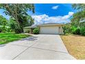 Wide concrete driveway leading to a 2-car garage and a charming home exterior with manicured landscaping at 2512 Jamaica St, Sarasota, FL 34231