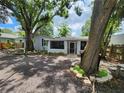 View of charming gray home with mature trees, landscaping, and a screened-in porch at 27 Tucker Ave, Sarasota, FL 34232