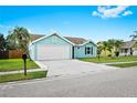 Charming aqua home showing a two-car garage, well-kept lawn, and simple landscaping at 3551 65Th Avenue E Cir, Sarasota, FL 34243