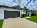 Contemporary home showcasing a spacious driveway leading to an attached two-car garage and well-manicured lawn at 3616 Bellefonte Ave, North Port, FL 34286