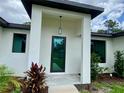 Inviting home entrance featuring a modern glass front door, manicured landscaping, and stylish exterior lighting at 3616 Bellefonte Ave, North Port, FL 34286