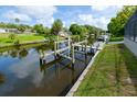 A private dock with a boat lift sits on a calm canal, surrounded by lush landscaping and nearby homes at 3636 Mineola, Sarasota, FL 34239