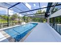 A screened-in pool area features a long pool, sleek decking, and views of the canal and landscaping beyond at 3636 Mineola, Sarasota, FL 34239