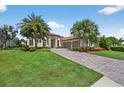 Beautiful home featuring manicured lawn, stone driveway, tropical landscaping, and a neutral color scheme at 5104 Benito Ct, Bradenton, FL 34211