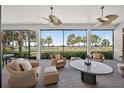 Screened lanai with ceiling fans and comfortable seating offers relaxing views of lush landscaping and golf course at 5104 Benito Ct, Bradenton, FL 34211