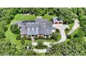 Aerial view of a luxury home surrounded by trees with a pool, circular drive, and separate garage at 6050 Saddle Oak Trl, Sarasota, FL 34241