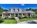 Charming gray home featuring manicured landscaping, stone accents, dormer windows, and a grand entrance at 6050 Saddle Oak Trl, Sarasota, FL 34241