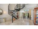 Elegant foyer with a striking spiral staircase, marble floors, and a view into the light-filled living room beyond at 6905 Pine Valley St, Bradenton, FL 34202