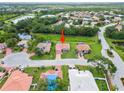 Aerial view of a single-Gathering home with a red tile roof nestled in a peaceful neighborhood with a nearby lake at 7115 39Th E Ln, Sarasota, FL 34243
