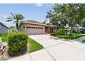 Well-maintained home with a two-car garage, mature trees, and lush green lawn at 1415 Millbrook Cir, Bradenton, FL 34212