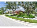 Well-kept home with mature trees, a green lawn, and neat landscaping at 1415 Millbrook Cir, Bradenton, FL 34212