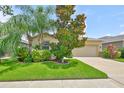 Inviting exterior featuring lush landscaping, a well-maintained lawn, and a classic tan facade at 2450 Dovesong Trace Dr, Ruskin, FL 33570