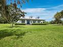 Beautiful white home with metal roof, blue front door, manicured lawn and mature trees offer the home great curb appeal at 3100 Lena Ln, Sarasota, FL 34240