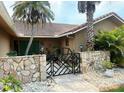 Charming home entrance with a decorative gate, stone walls, and tiled roof at 3764 Torrey Pines Blvd, Sarasota, FL 34238