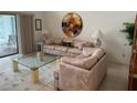Inviting living room features a plush sofa, glass coffee table, and a round art piece above the sofa at 3764 Torrey Pines Blvd, Sarasota, FL 34238