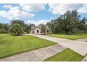Spacious driveway leading to a charming two-story home featuring a lush green lawn and mature trees at 3906 Twin Rivers Trl, Parrish, FL 34219