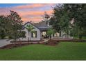 Charming two-story home featuring a lush green lawn and mature trees under an orange sunset at 3906 Twin Rivers Trl, Parrish, FL 34219