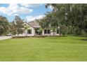 Charming two-story home featuring a lush green lawn and mature trees against a cloudy blue sky at 3906 Twin Rivers Trl, Parrish, FL 34219