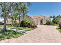 Well-maintained home featuring lush landscaping, mature trees, and a classic tile roof, with brick paver driveway at 5779 Wilena Pl, Sarasota, FL 34238