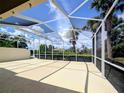 Spacious screened lanai with views of the lush backyard landscaping, blue sky, and the lake at 5779 Wilena Pl, Sarasota, FL 34238
