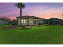 Expansive backyard with lush green grass and professionally landscaped garden beds and distant screened lanai at 7781 Grande Shores Dr, Sarasota, FL 34240