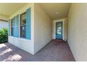Inviting entryway with brick pavers, a textured wall, and a blue front door with glass inserts at 7781 Grande Shores Dr, Sarasota, FL 34240