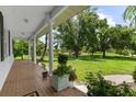 Inviting front porch with brick floor and white columns, offering picturesque views of the expansive lawn at 21705 67Th E Ave, Bradenton, FL 34211