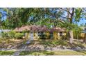 Inviting single-story home featuring a yellow exterior, white trim, and mature landscaping in a serene setting at 218 32Nd W St, Bradenton, FL 34205