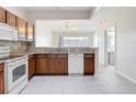 Well-lit kitchen featuring wood cabinetry, granite countertops, and tiled flooring at 26548 Castleview Way, Wesley Chapel, FL 33544