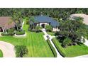 Aerial view of estate home with lush, manicured lawn, mature trees and bushes, and charming hardscape at 2962 Wilderness E Blvd, Parrish, FL 34219