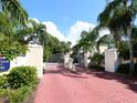 Elegant gated entrance with lush landscaping and red brick pathway leading to the community at 3954 Hamilton Club Cir # 14, Sarasota, FL 34242