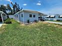 Light blue single story home with a well-kept lawn and a carport under a blue sky at 5316 Chateau Ln, Bradenton, FL 34207