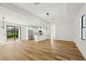 Open-concept living room with hardwood floors and views of the modern white kitchen at 5386 Easter Ter, North Port, FL 34286