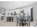 Eat-in kitchen featuring white cabinets, pendant lighting, an island with seating, and a dining table at 5981 Amberly Dr, Bradenton, FL 34208