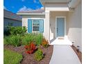 Attractive home entrance with blue door and shutters, lush landscaping, and a well-manicured lawn at 10177 Crystal Isle Cir, Sarasota, FL 34241