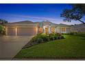 Charming home exterior at dusk, showcasing a well-lit facade, three-car garage, and lush landscaping at 11250 Rivers Bluff Cir, Lakewood Ranch, FL 34202