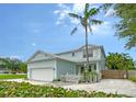 Charming two-story home with light blue siding, a white picket fence, and a well-manicured front yard with palm tree at 1738 Siesta Dr, Sarasota, FL 34239