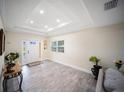 A bright living room with tray ceilings, wood-look tile flooring, and a large window at 204 21St Ne St, Bradenton, FL 34208