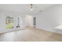 Spacious living room with light wood-look floors, ceiling fan, and large windows allowing for ample natural light at 4250 Winfall Ave, North Port, FL 34286